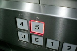 Nahaufnahme eines Bedienfelds eines Aufzugs. Die Taste für die 5. Etage leuchtet rot umrahmt.